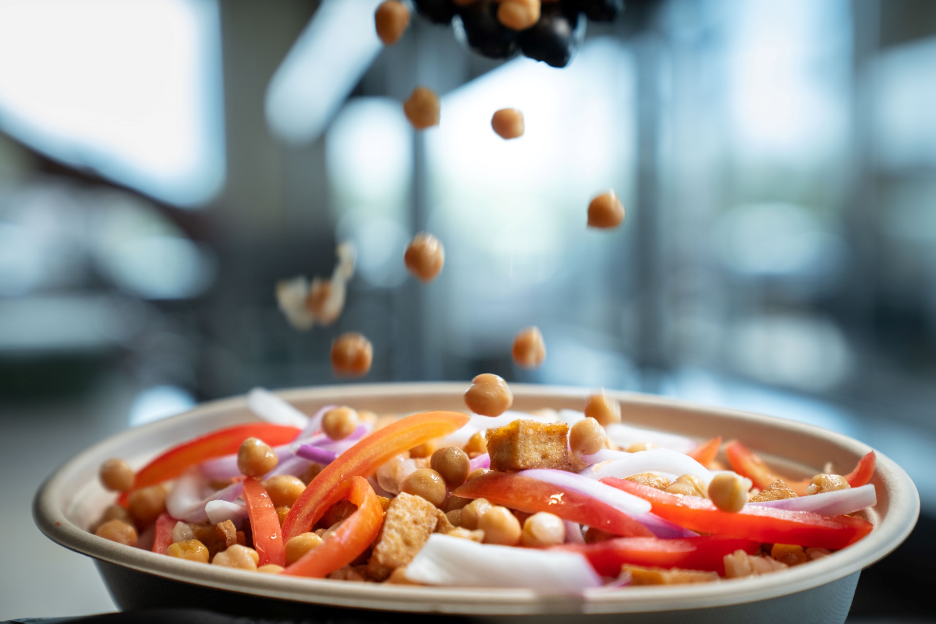 Chef at Balance Grille in Cleveland preparing a power bowl with chickpeas and clean, plant-based ingredients.