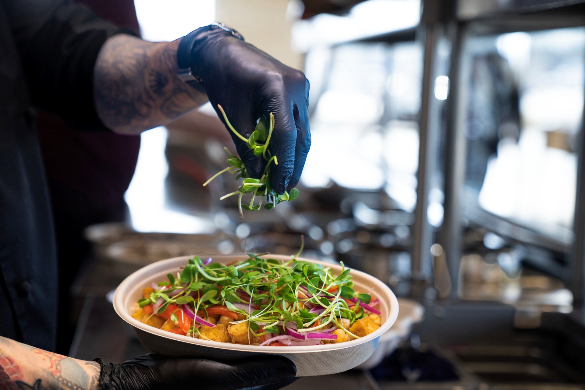 Chef at Balance Grille adding microgreens to a customizable bowl made with fresh, locally sourced ingredients.